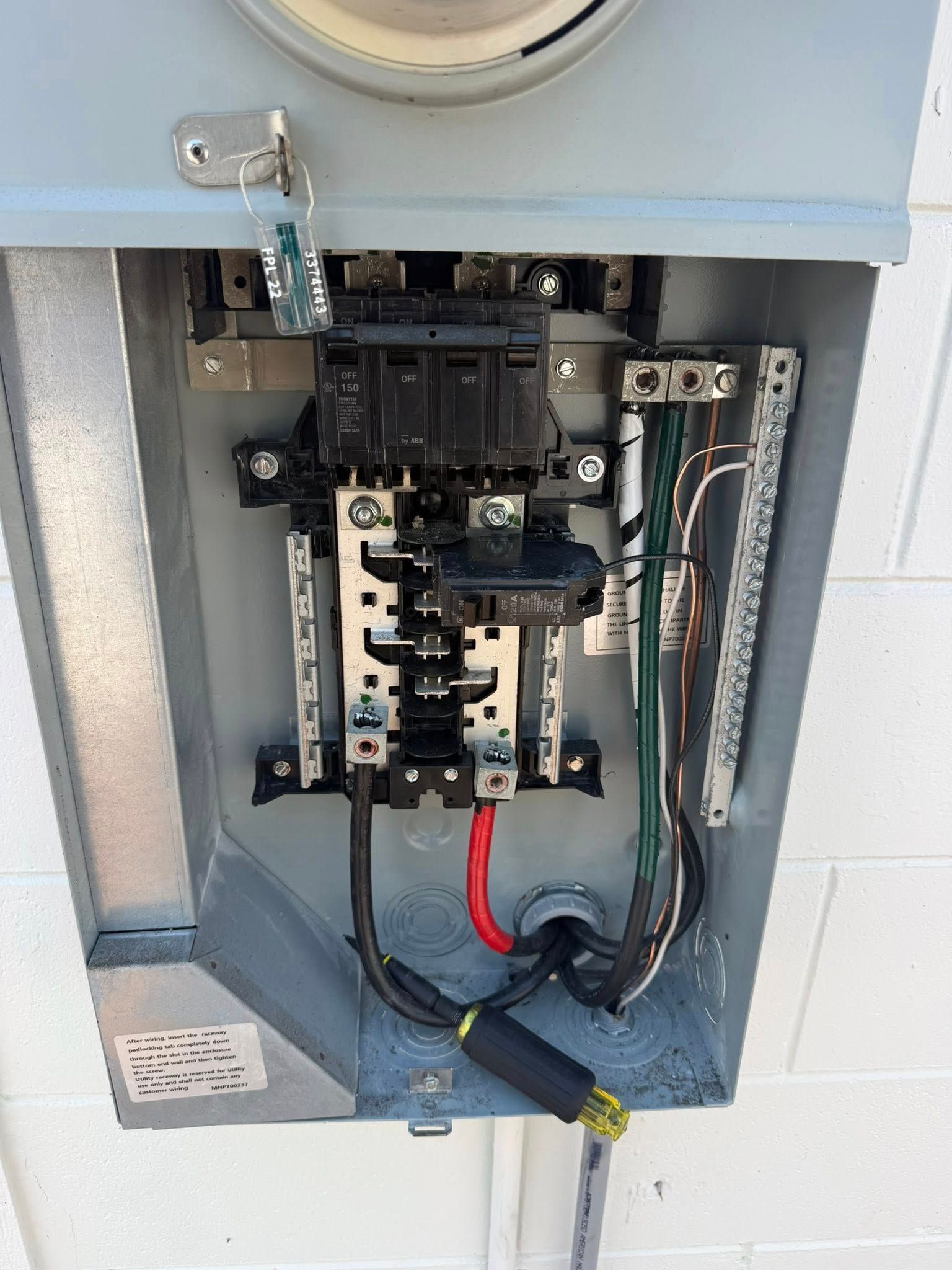 Open electrical panel with wiring, breakers, and conduit inside a gray utility box.