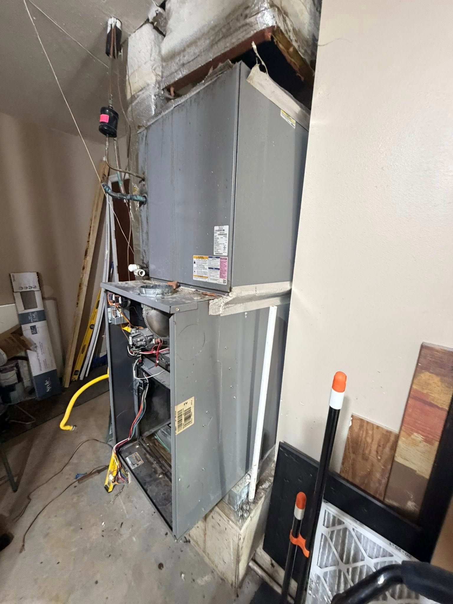 Installed HVAC furnace unit in a utility closet, with ductwork, wiring, and tools nearby.