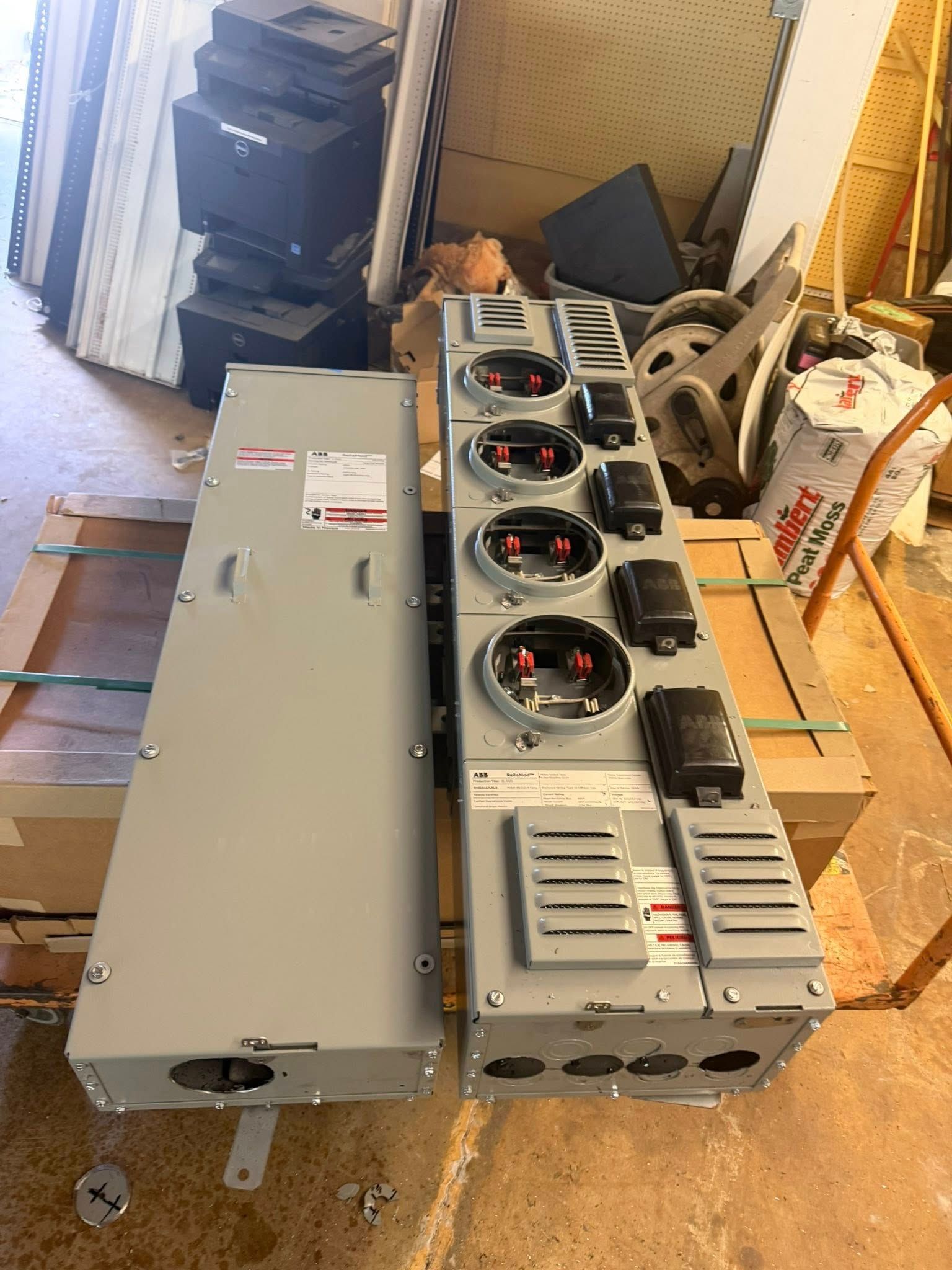 Row of industrial metal battery or power modules on a wooden floor in a workshop.
