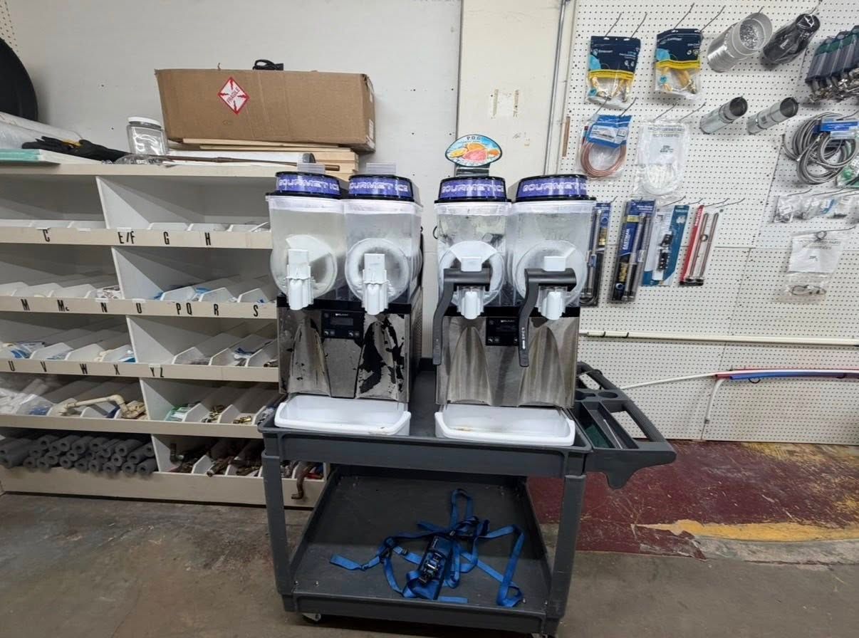 Three white countertop drink dispensers on a store shelf in a retail aisle
