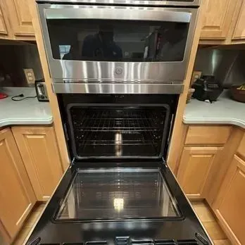 Built-in stainless steel double oven with the lower door open in a kitchen.