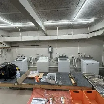 Laundry room with several washing machines, utility sink, and tools on a workbench