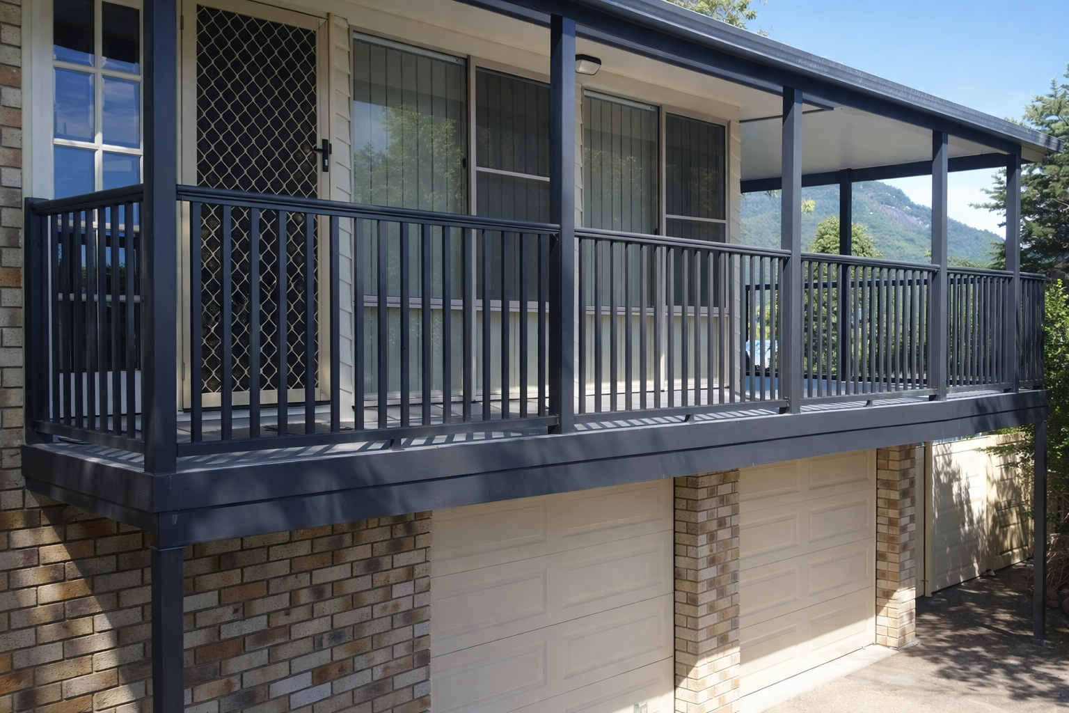 Second-floor balcony with black railings above a brick garage, attached to a house