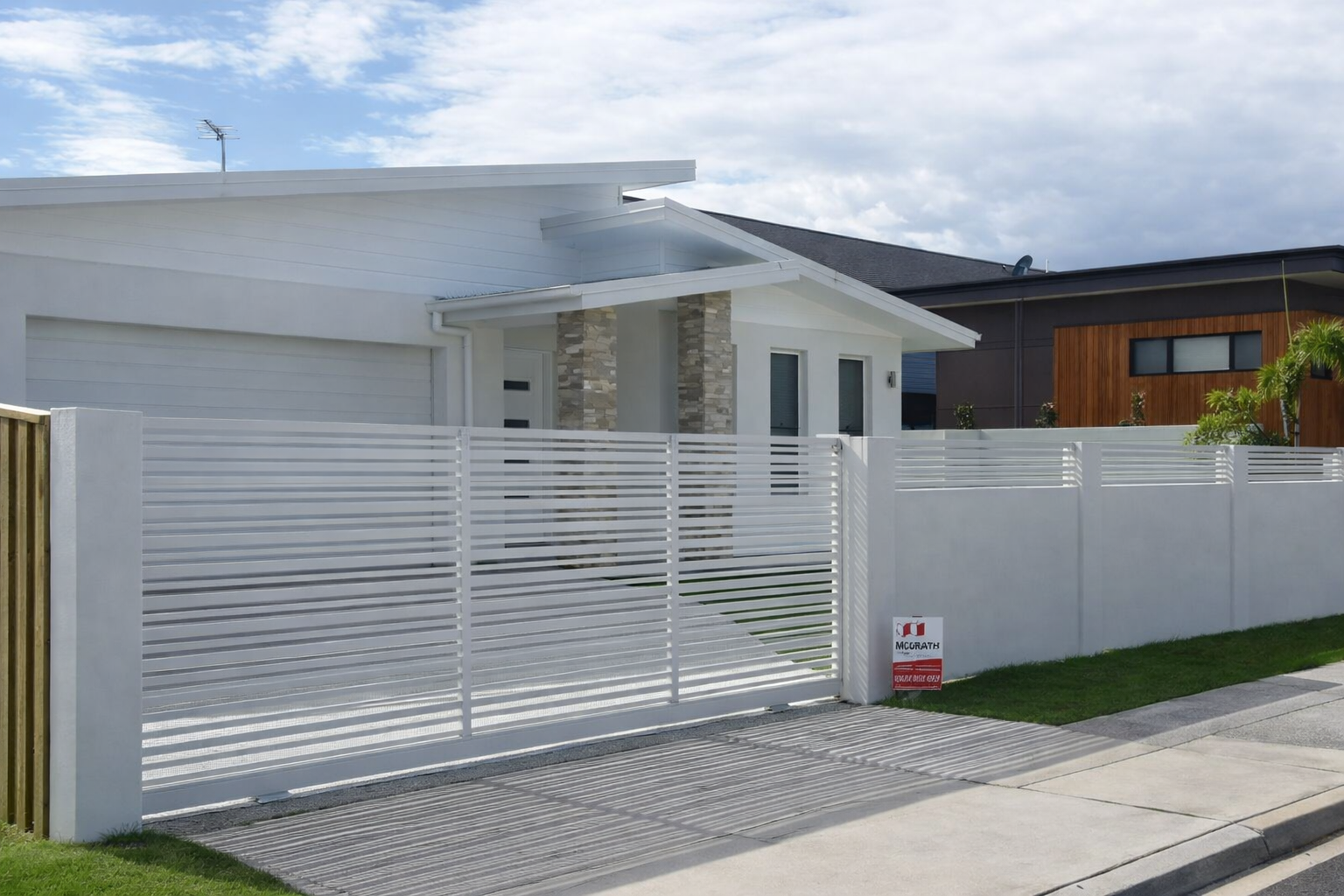 White Fence Around A Grey House With A Grassy Yard — Frontline Fences in Tweed Heads South, NSW
