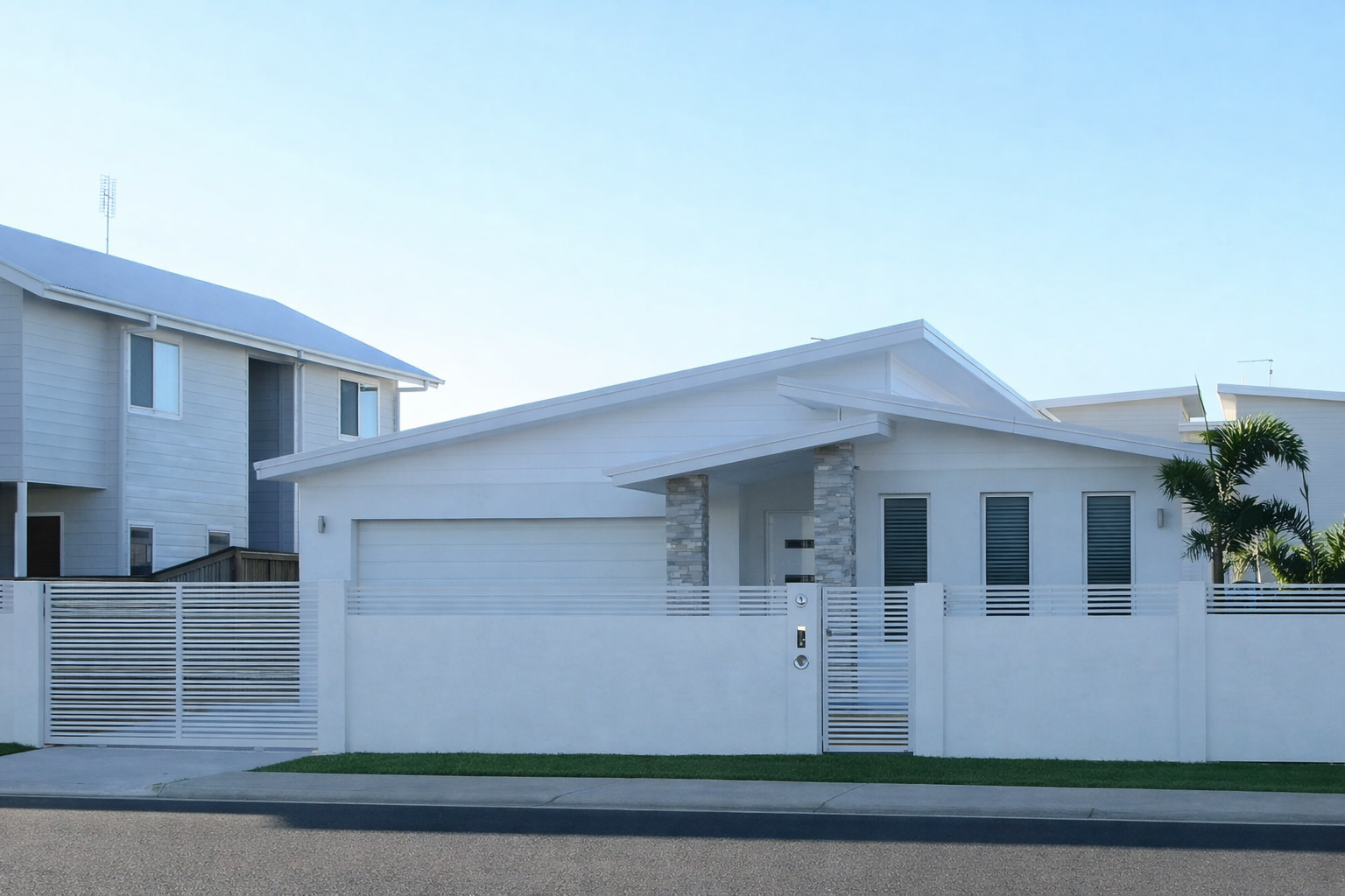 Modern white house with a garage, front gate, and small lawn by the street