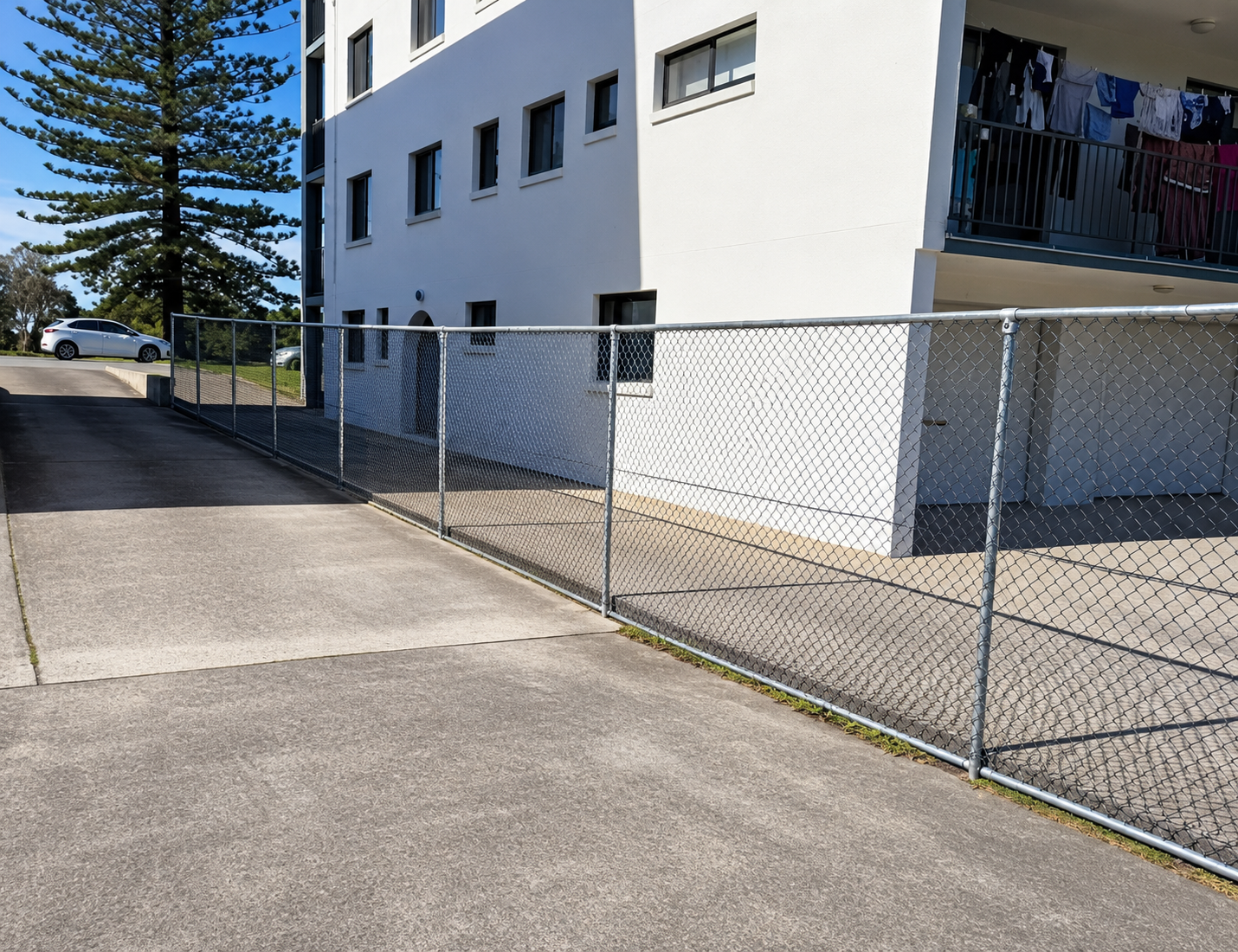 Chain-link Fence Along a Sidewalk Beside a White Apartment Building — Frontline Fences in Tweed Heads South, NSW
