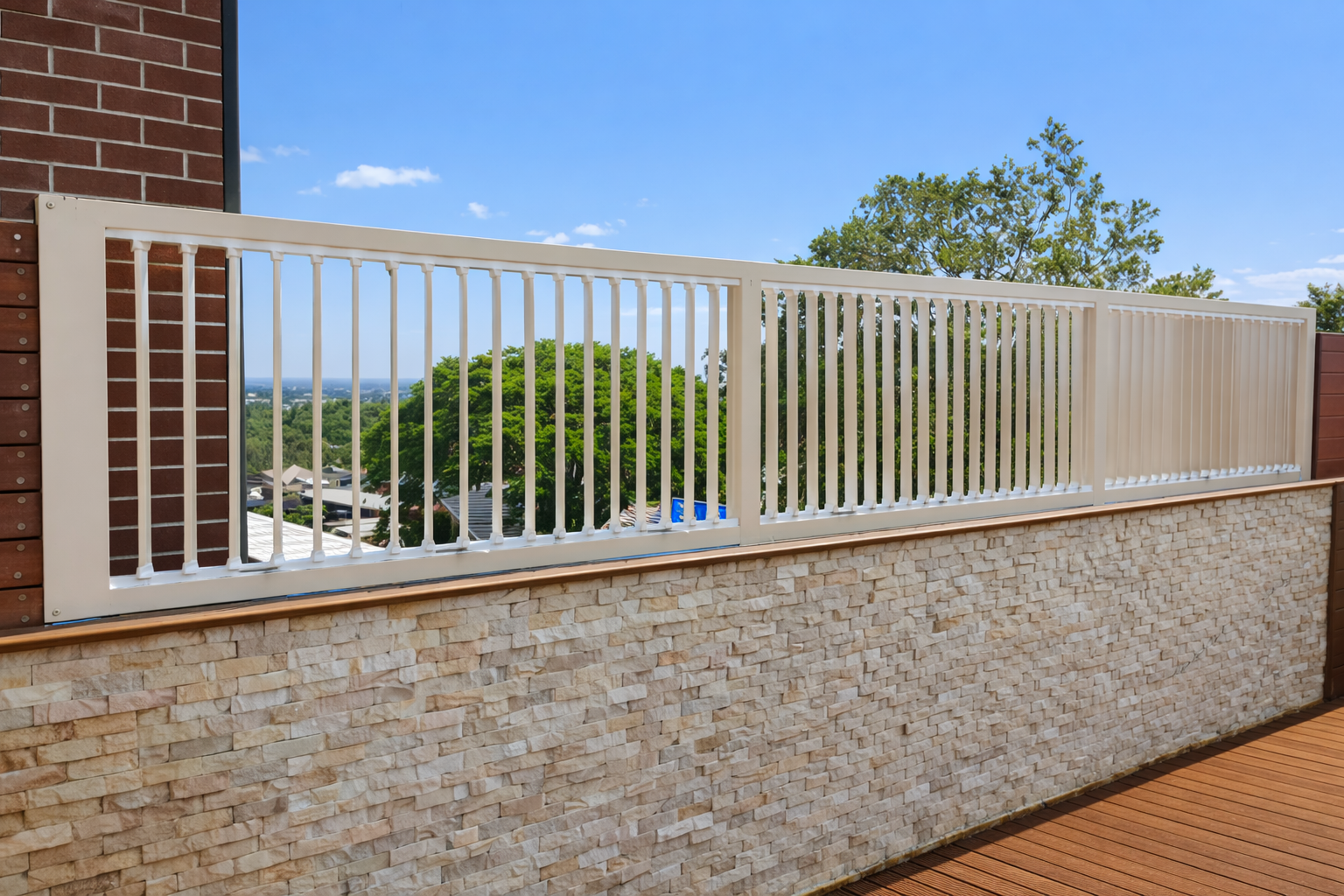 White balcony railing above a stone wall, overlooking trees and parked cars under a blue sky