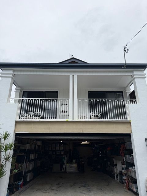 Two-story white house with a covered balcony and open garage under a cloudy sky — Frontline Fences in Tweed Heads South, NSW