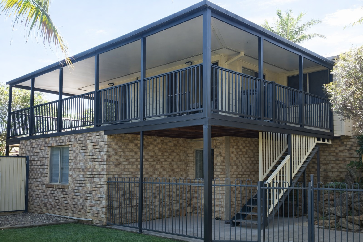 Two-story house with a covered upper deck and exterior stairs on a stone base