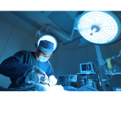 Surgeon performing operation under bright blue operating room lights.
