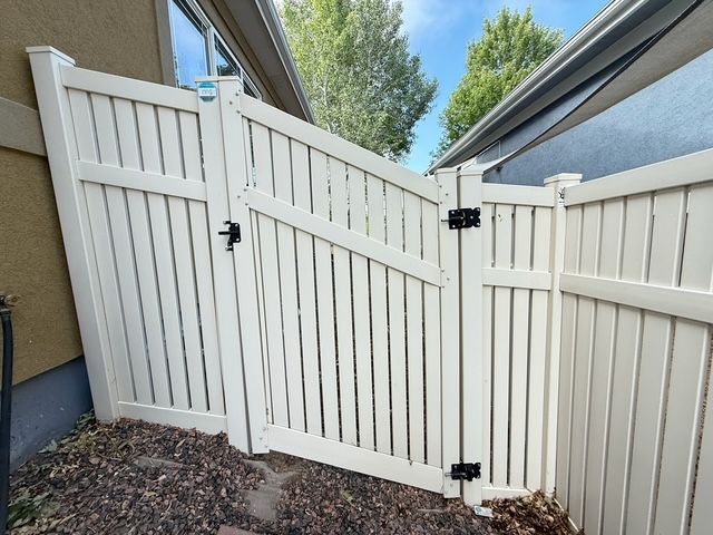 White vinyl fence with gate, near a building.