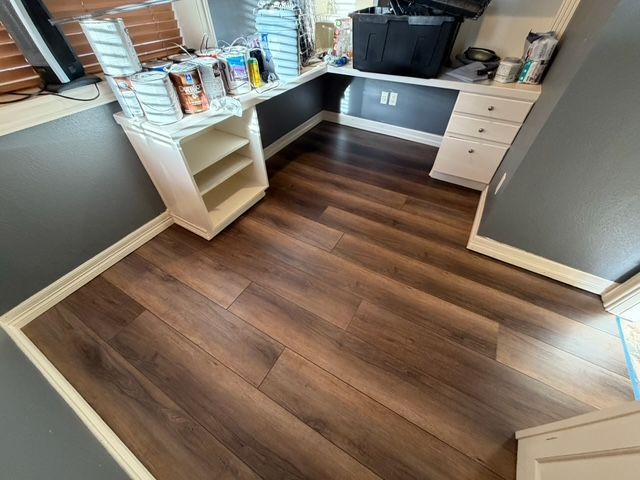 Dark wood-look flooring in a room with a built-in desk and white cabinets.