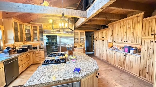 Kitchen with light wood cabinets, granite countertops, and stainless steel appliances.