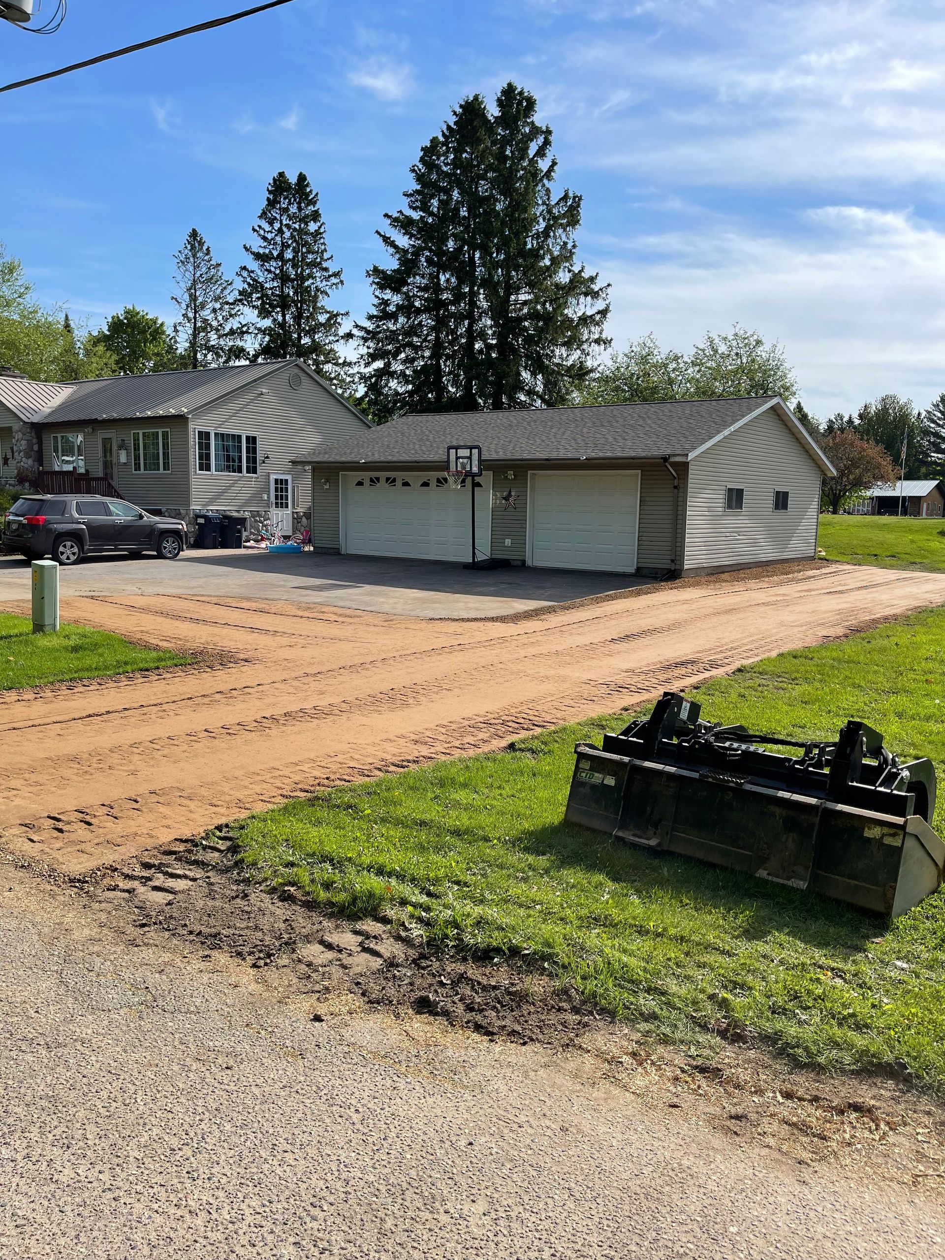 Dirt driveway and garage under construction in front of a house.