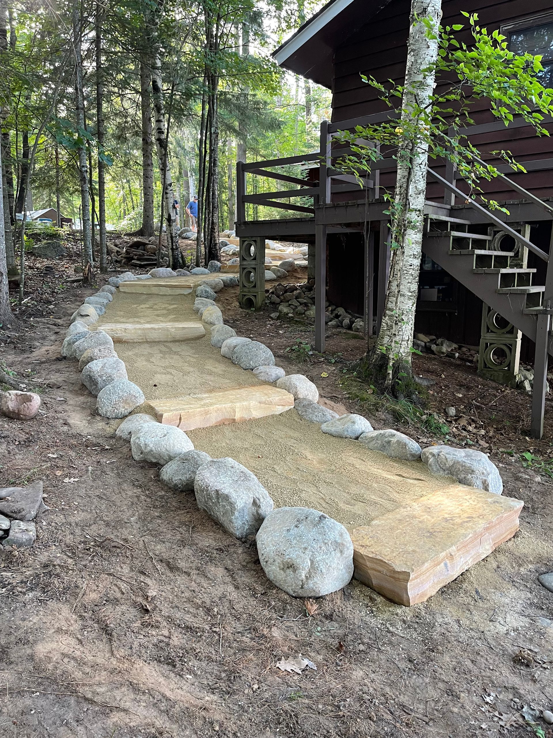 Stone path and steps leading to a wooden cabin in a wooded area.