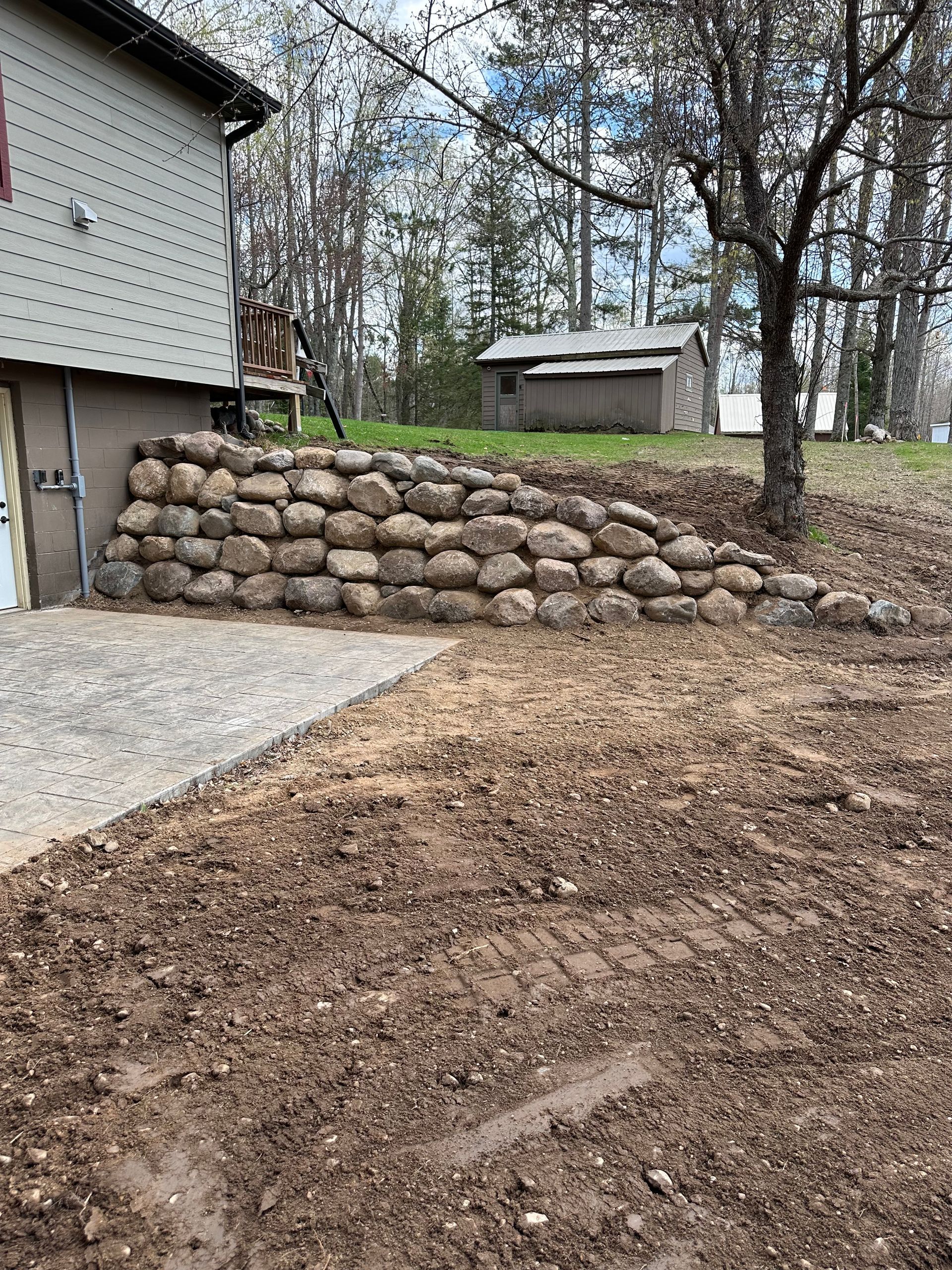 Stone retaining wall outside a building, with a dirt yard.
