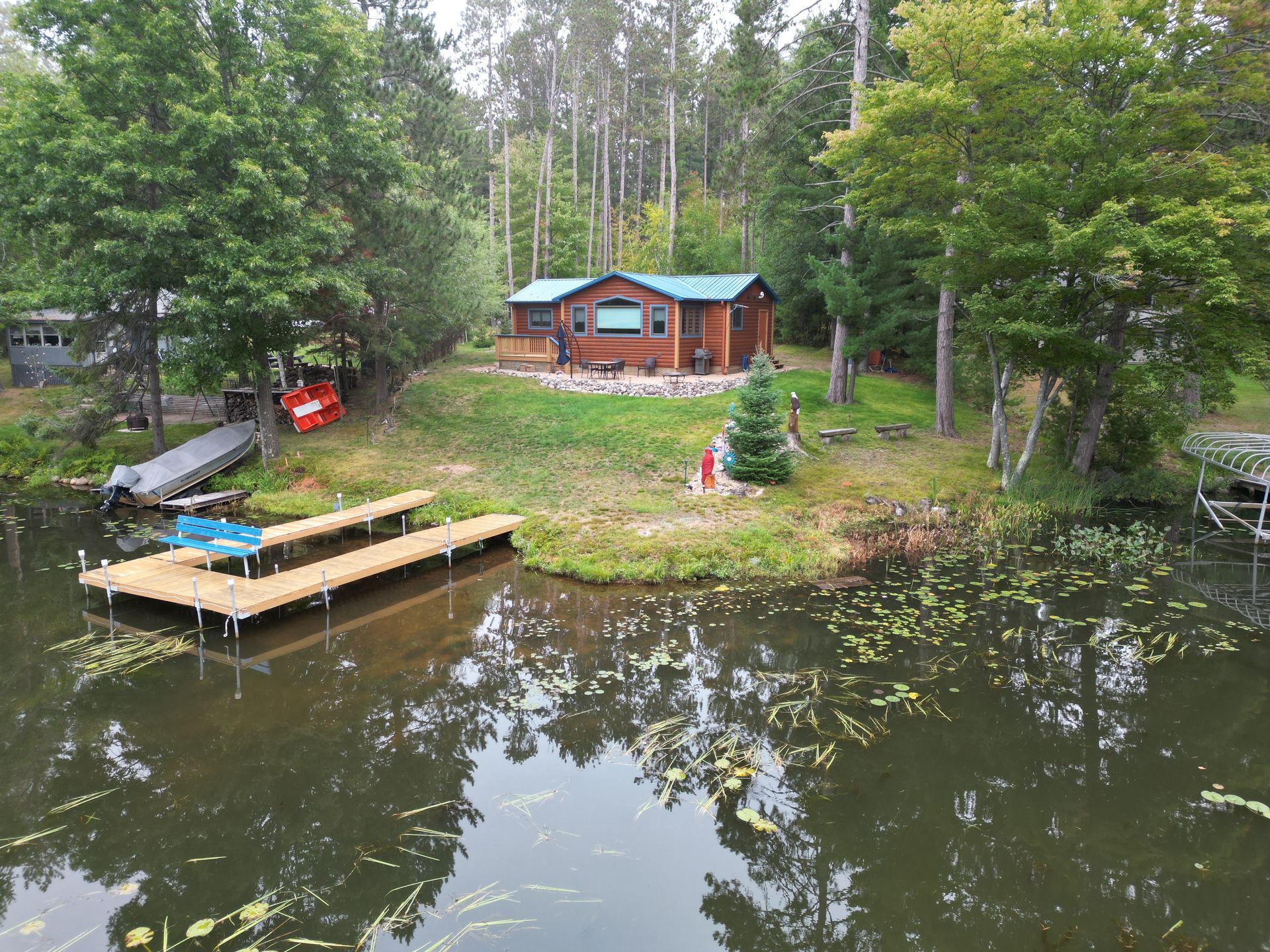 A cabin on a lake with a dock, surrounded by trees.