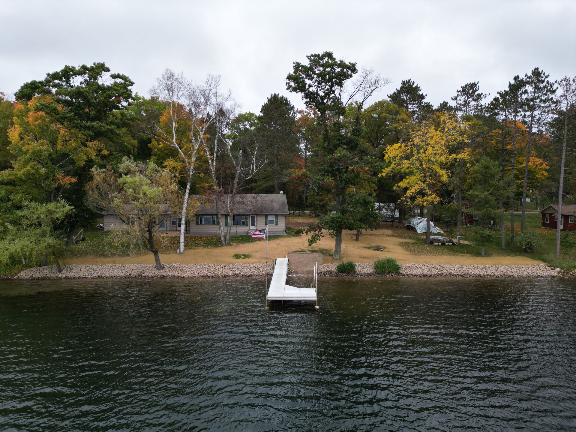Waterfront house with dock surrounded by trees and lake.