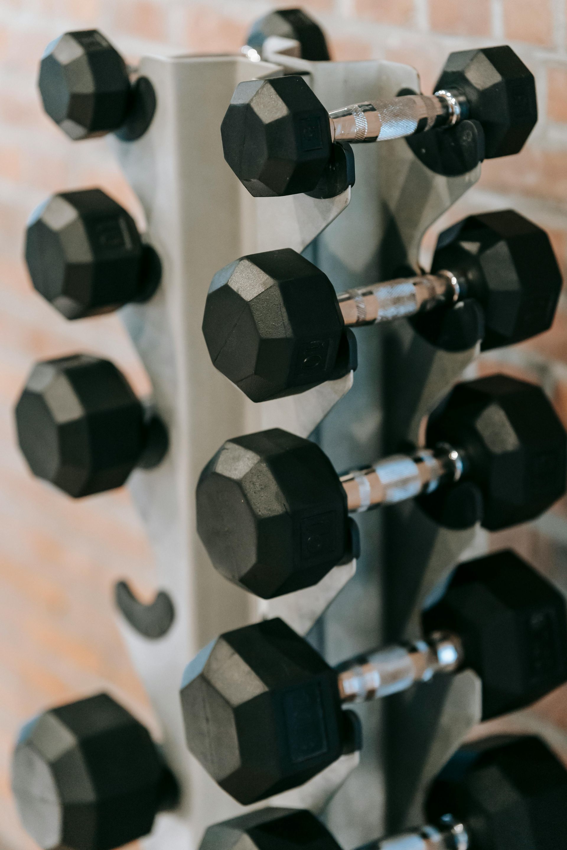 Gym with exercise machines, large windows overlooking a pool, and black flooring.