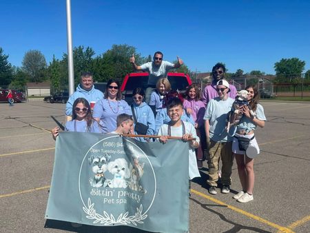 Group of people holding a banner with dog images. Outdoor sunny setting.