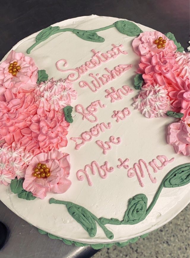 A cake with pink flowers and green leaves on it