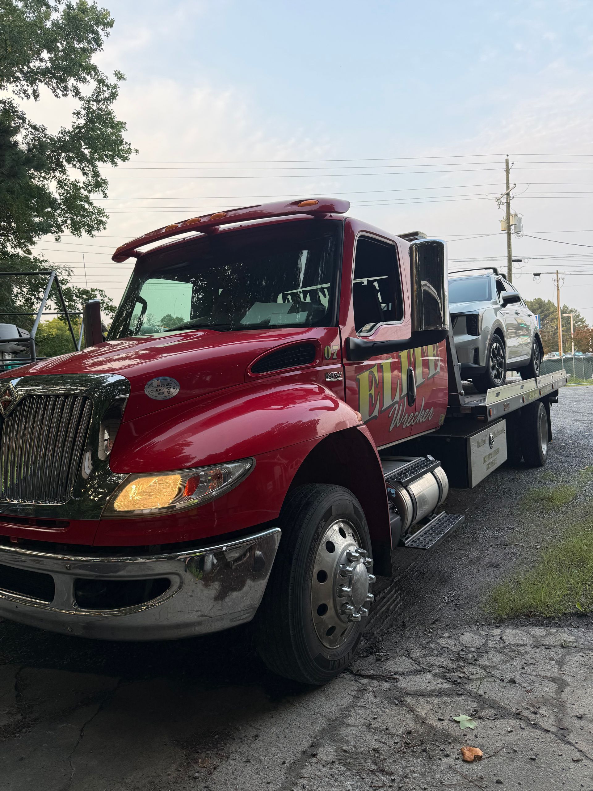 Red tow truck carrying a white pickup on a roadside
