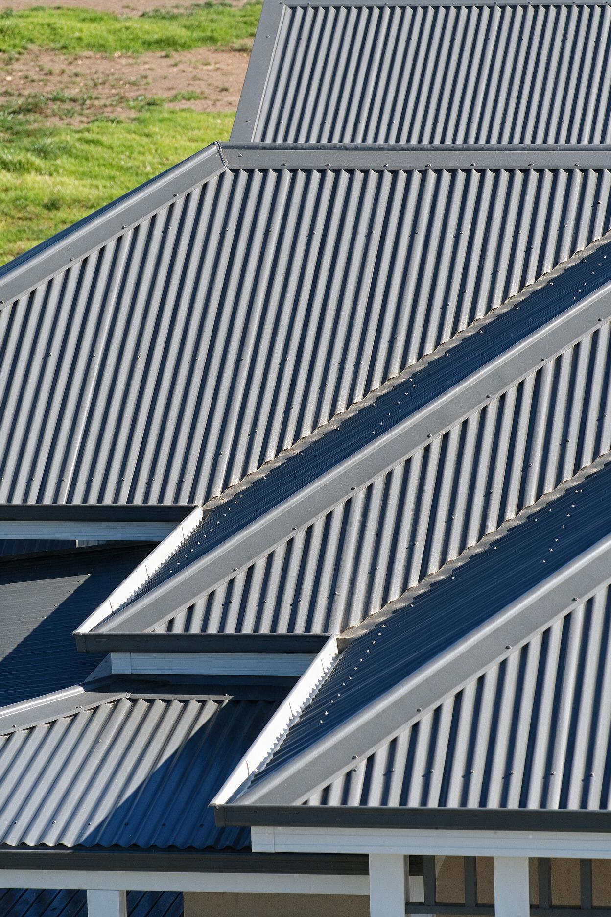Close-up of gray corrugated metal roofing on a house with intersecting gabled sections