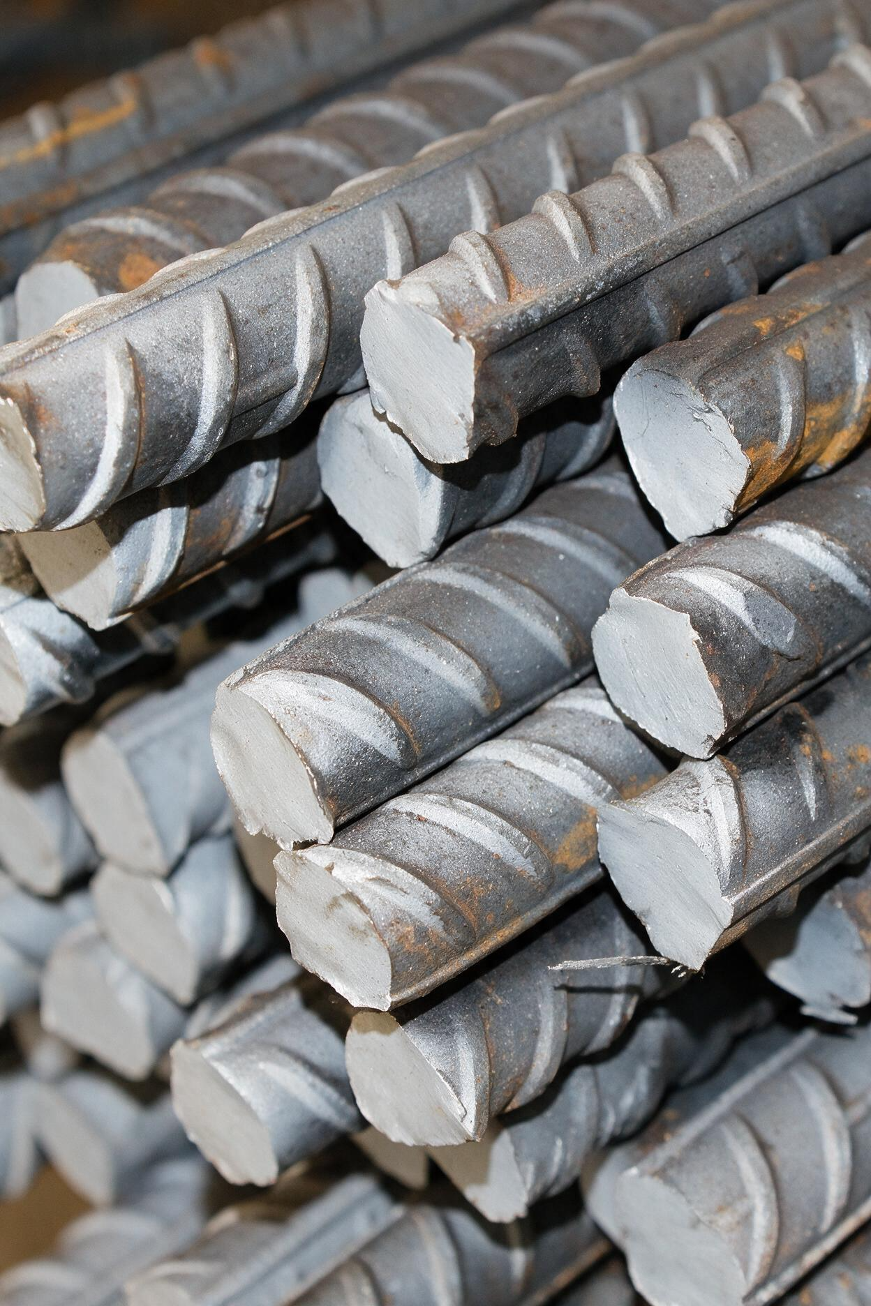 Stacked gray steel rebar rods with ridged ends in close-up