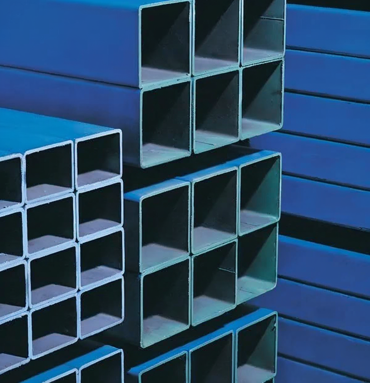 Blue metal shelving with stacked rectangular steel tubes in a workshop or warehouse