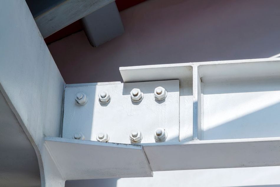 White metal beam joint with bolts and nuts on a structural frame in bright sunlight