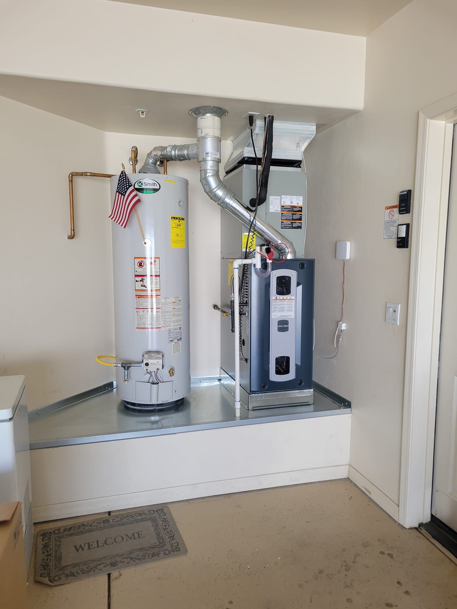Water heater and HVAC unit in a small utility closet with metal ducting and a raised platform.
