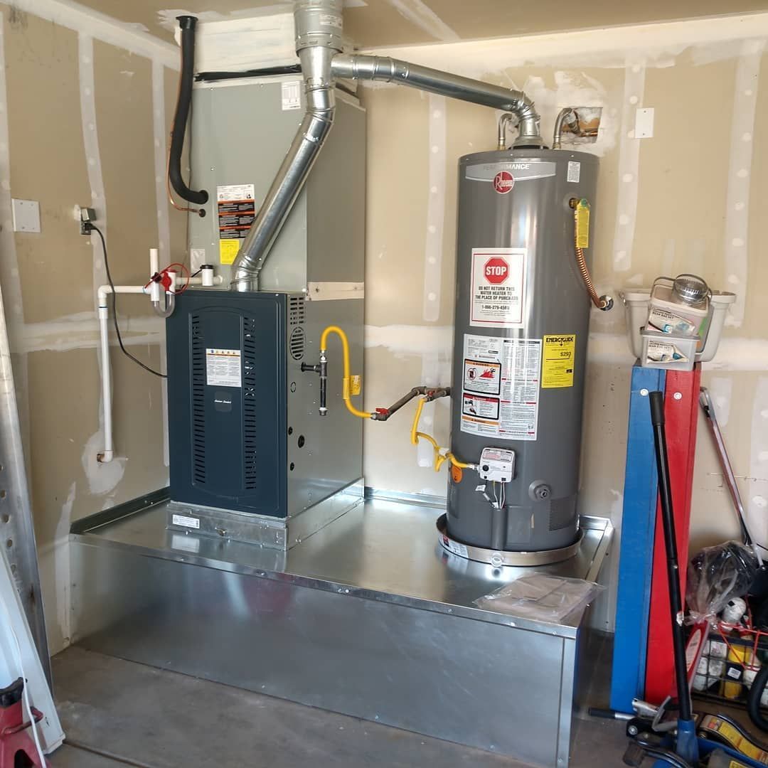 Utility room with a furnace and water heater connected by metal ductwork and piping on a concrete floor.