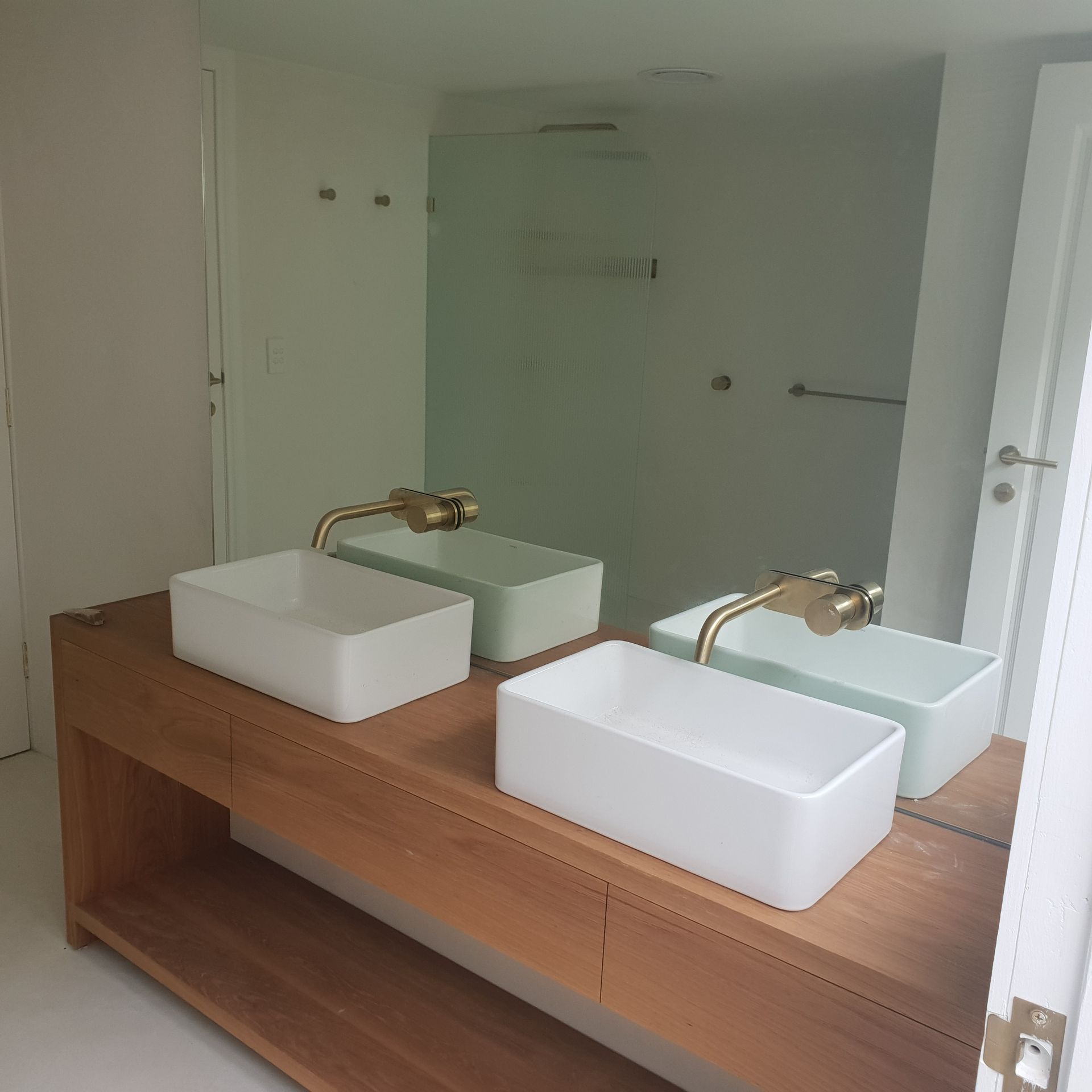 Modern bathroom vanity with two square sinks, brass faucets, and a large mirror