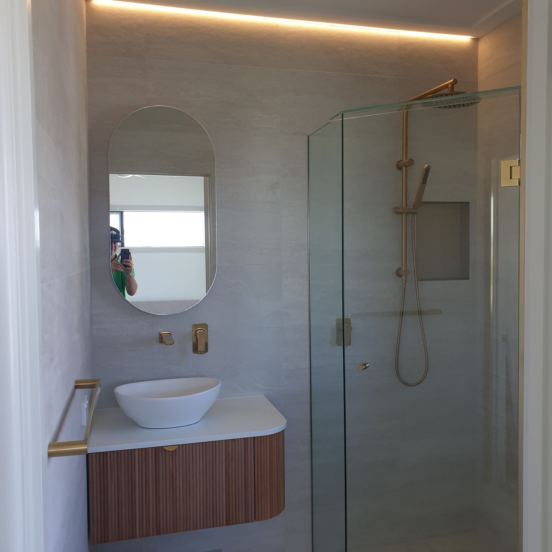 Modern bathroom with glass shower, wall mirror, and white vessel sink over wood vanity