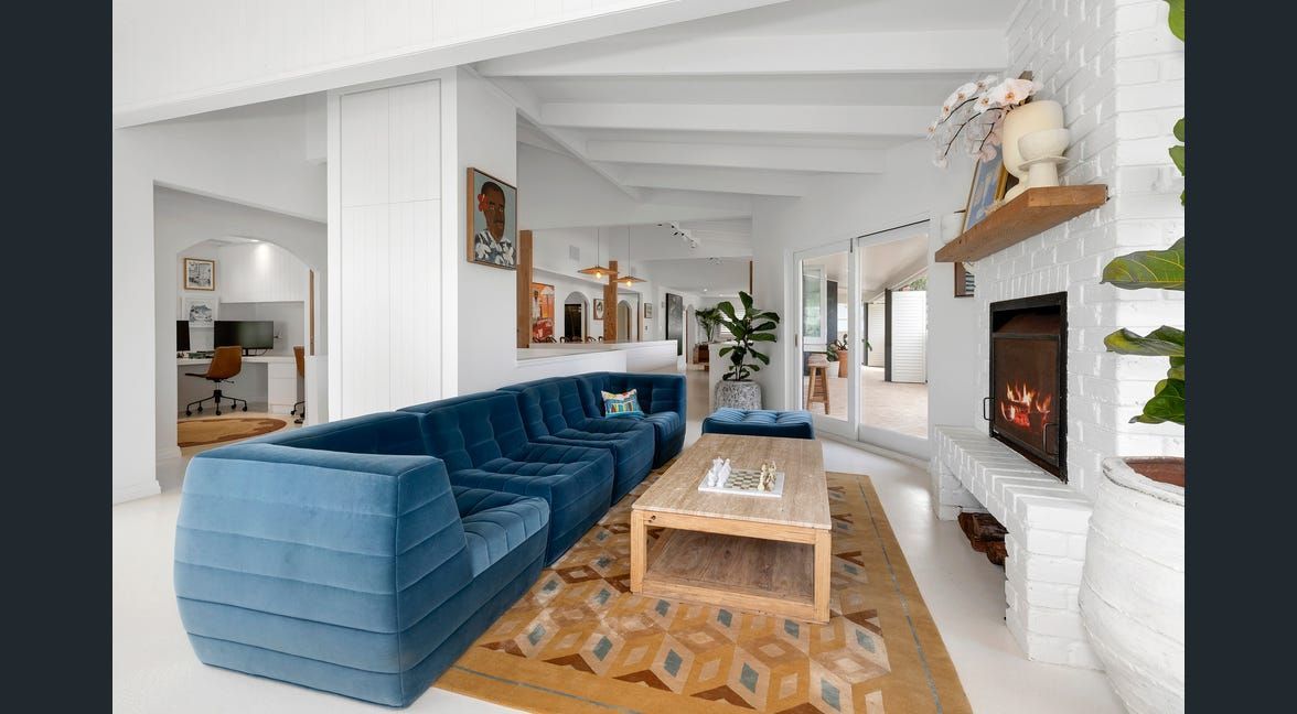 Bright living room with blue sectional sofa, wooden coffee table, white walls, and a fireplace