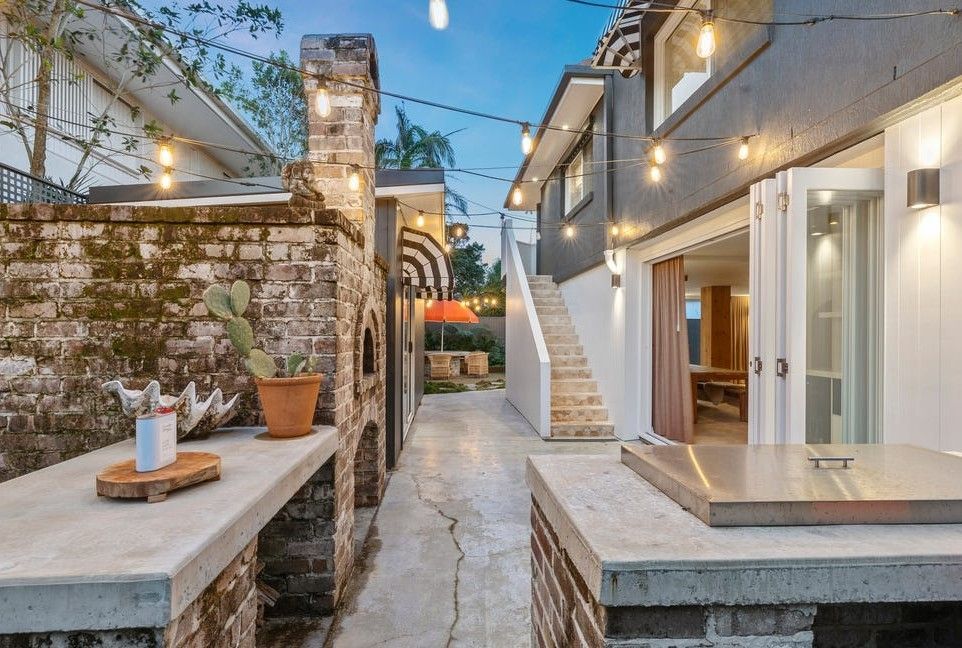 Modern courtyard with stone walls, outdoor stairs, and warm string lights at dusk
