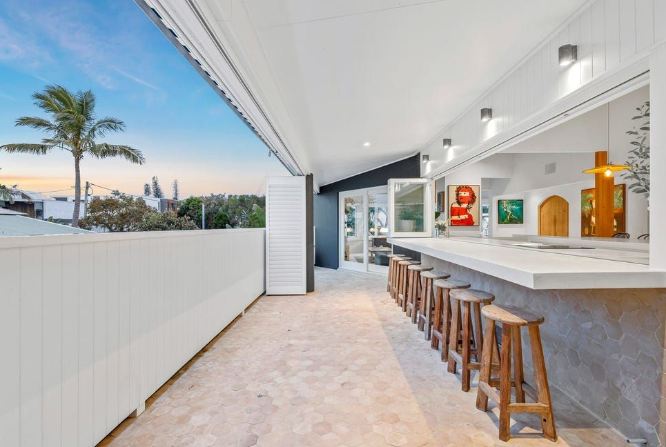 Modern Outdoor Bar Patio With Stools, White Walls, and a Slatted Awning at Sunset — Greg Pollard Building in Terranora, NSW