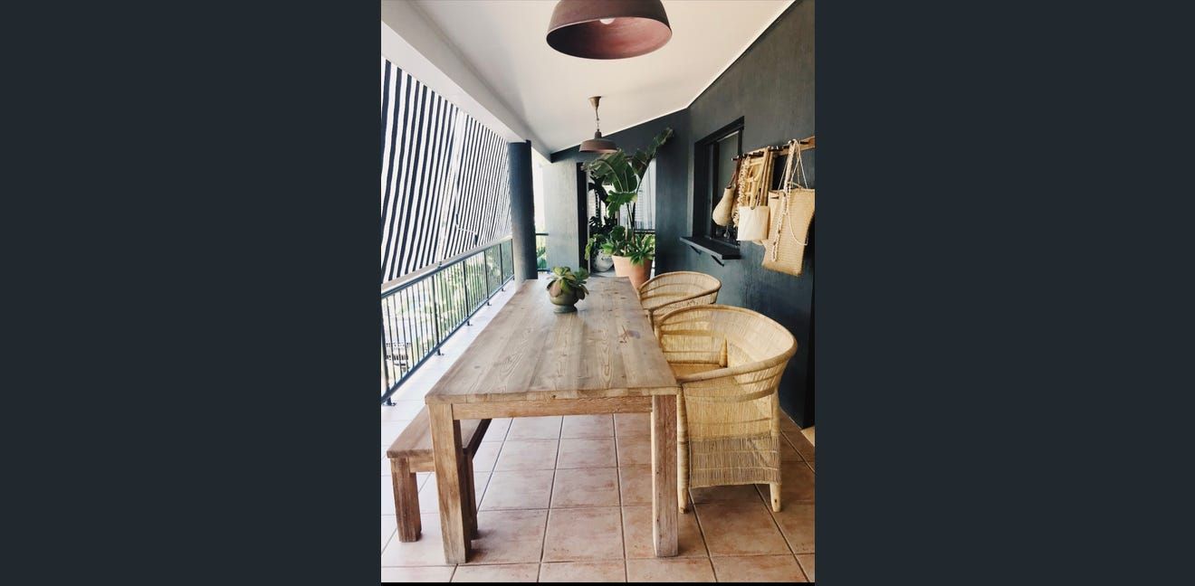 Narrow dining room with rustic wooden table, woven chairs, and patterned wall art in soft neutral tones