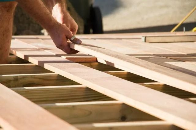 Hands Measuring Wooden Beams During a Construction Project — Greg Pollard Building in Bogangar, NSW