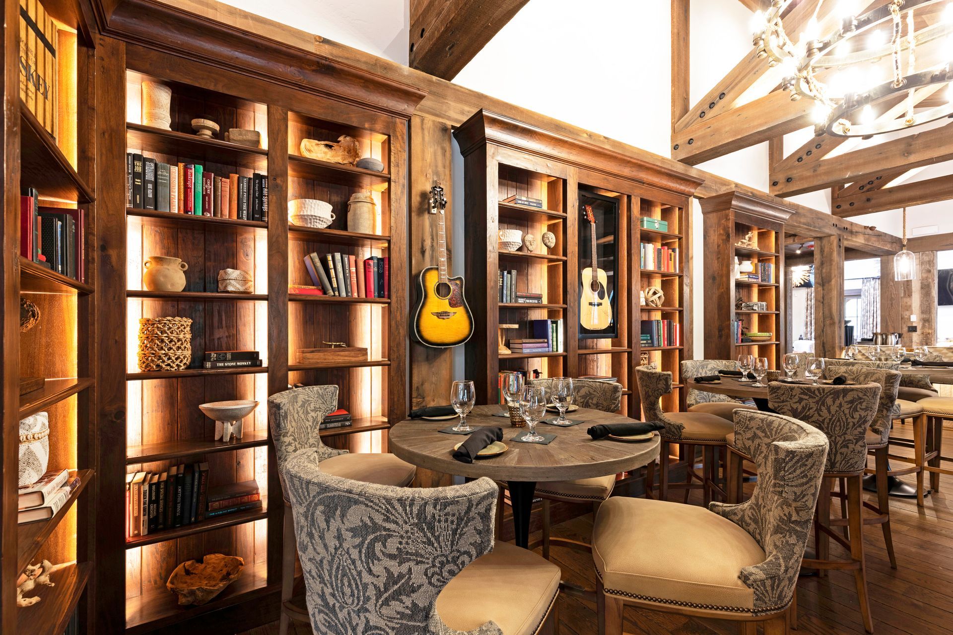 A dining room with tables and chairs and a guitar on the wall.