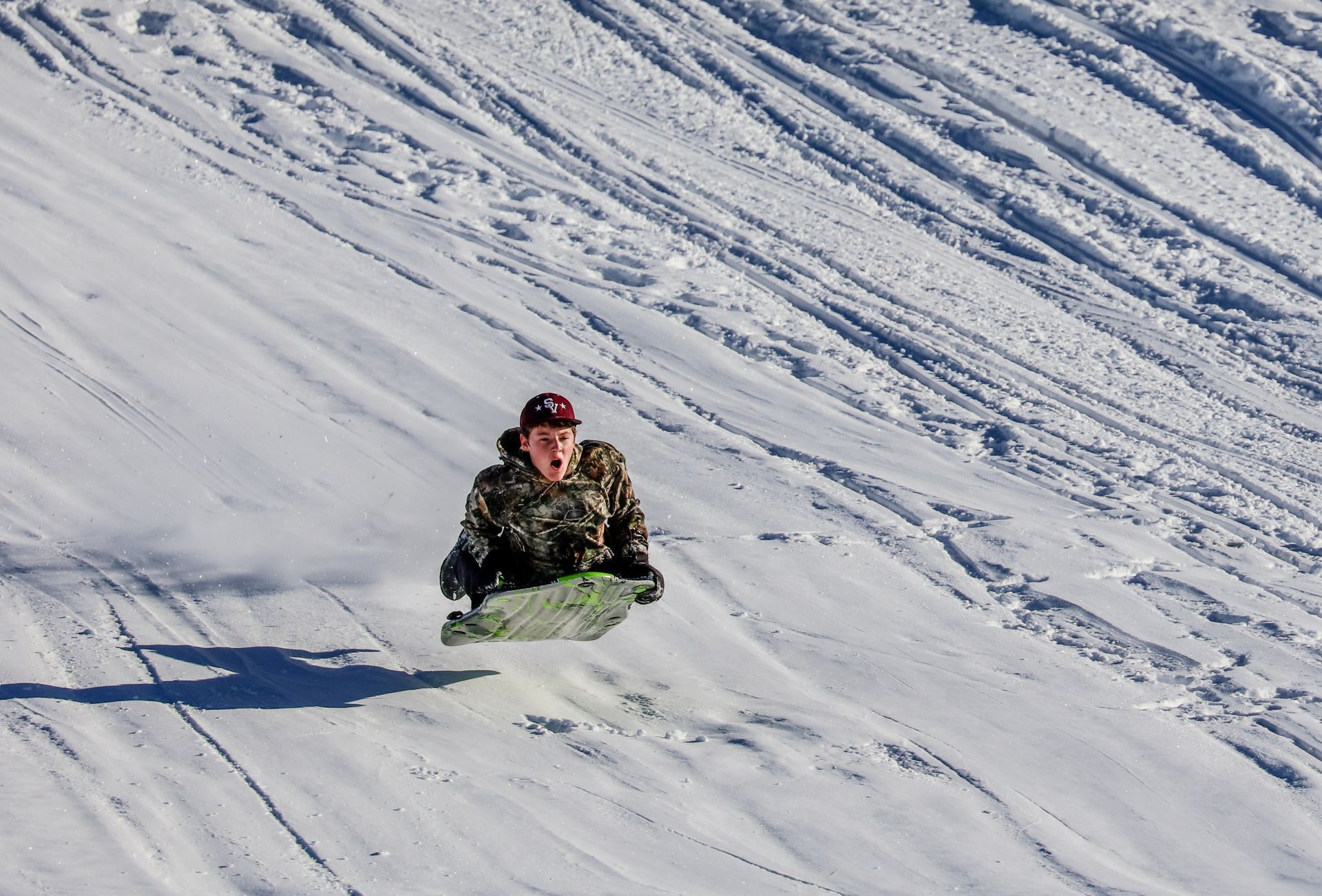 A person is sledding down a snow covered hill.