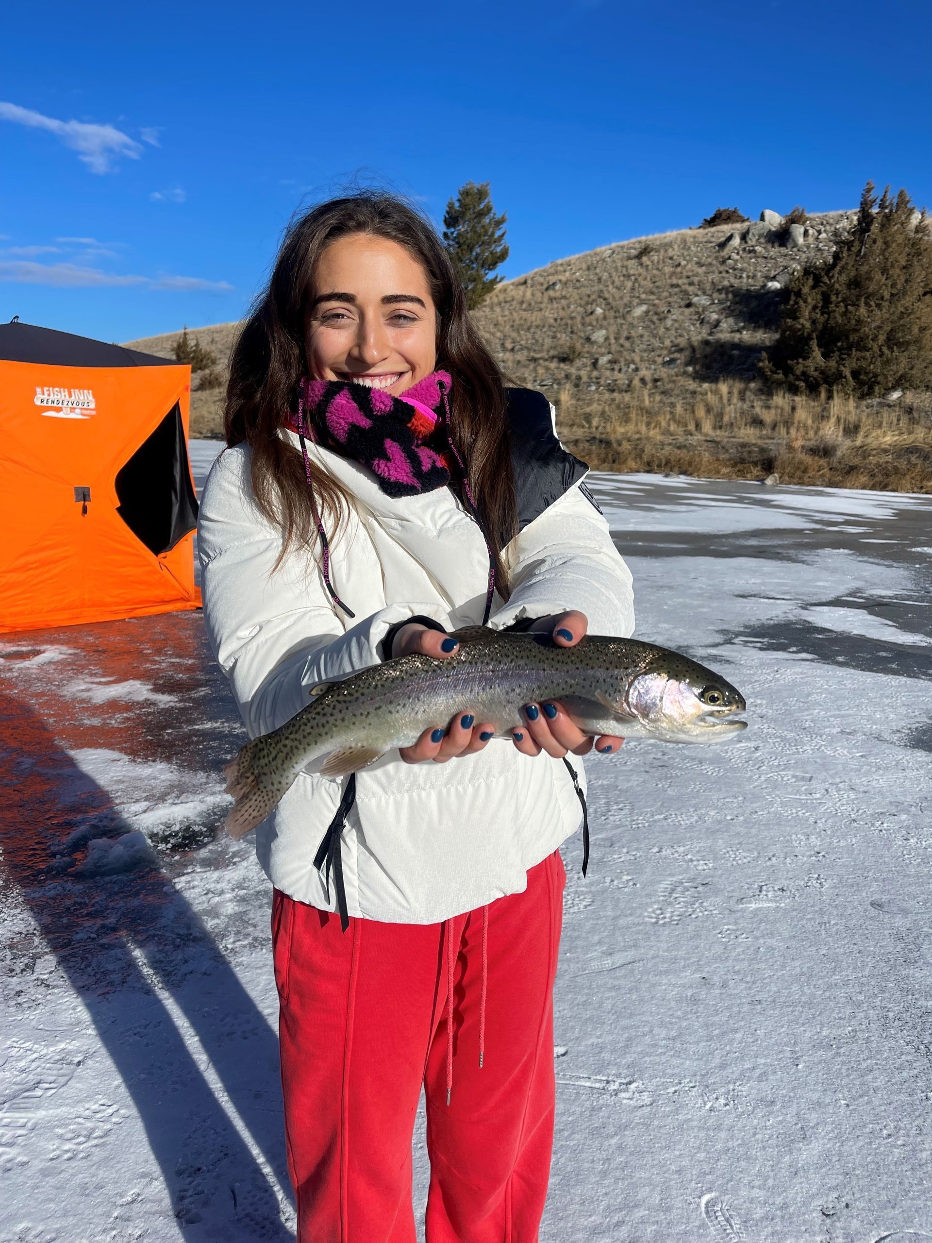 A woman is holding a fish in her hands in the snow.