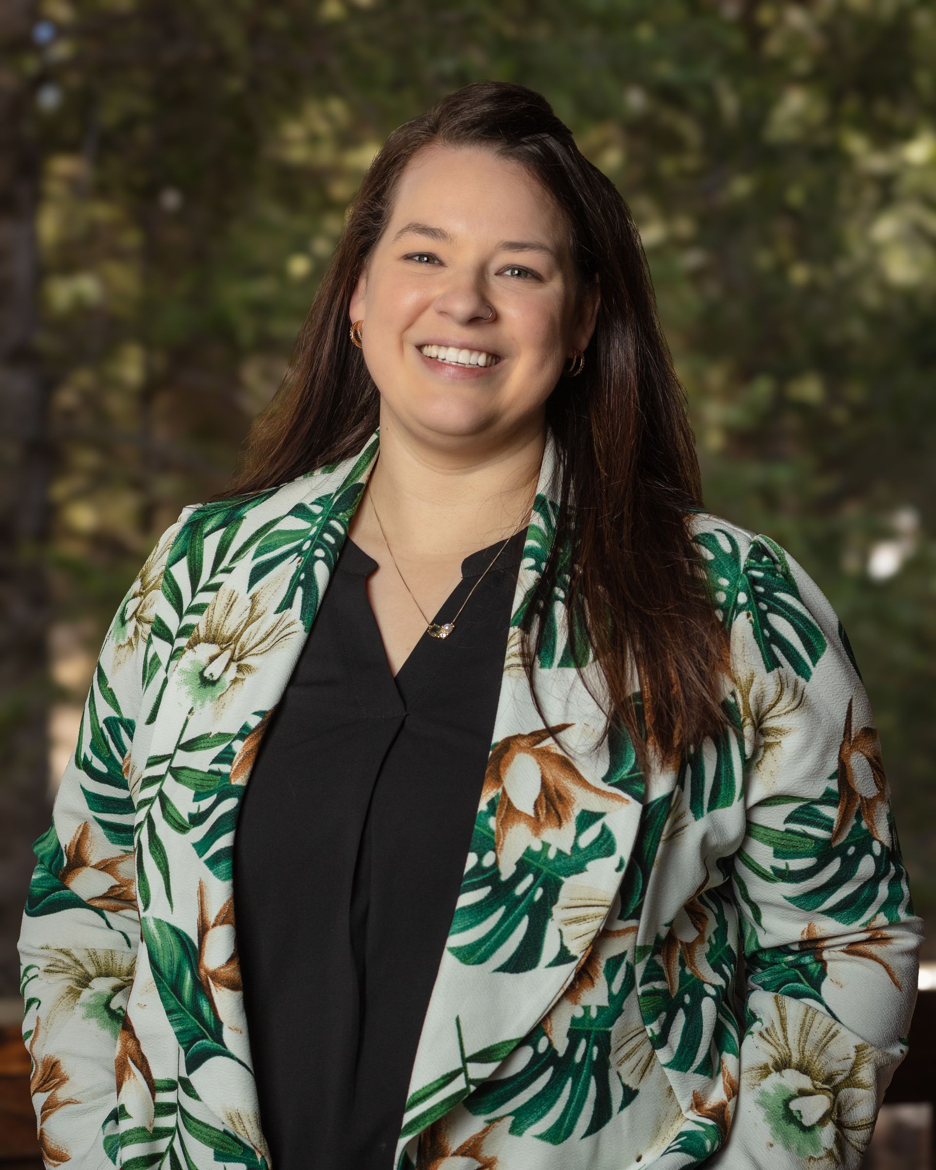 A woman wearing a floral jacket and a black shirt is smiling for the camera.