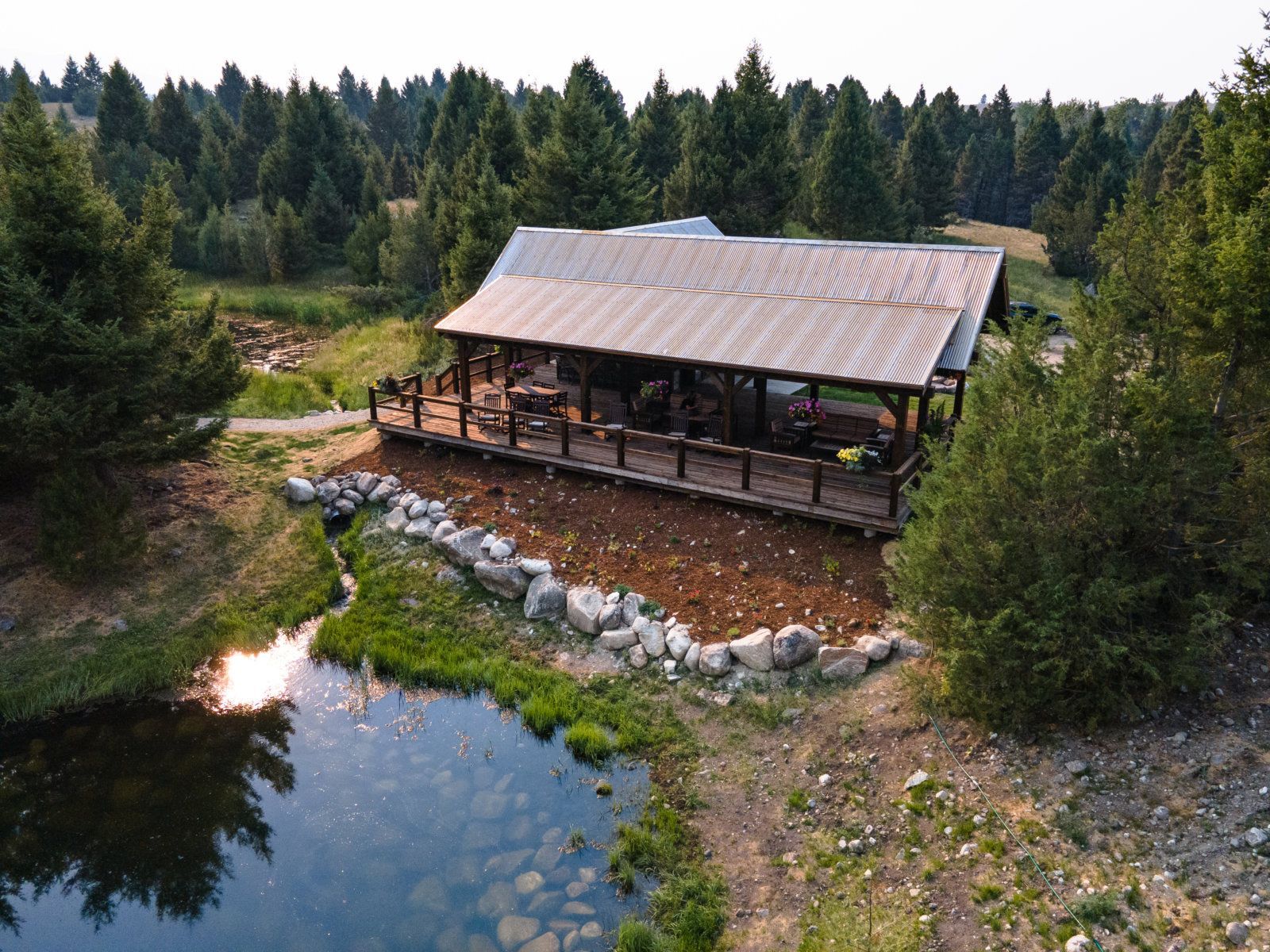 An aerial view of a house surrounded by trees and a pond