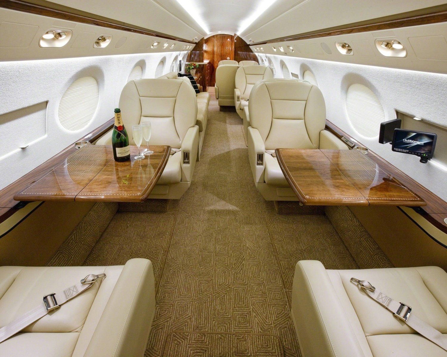 A bottle of champagne sits on a table in the middle of an airplane