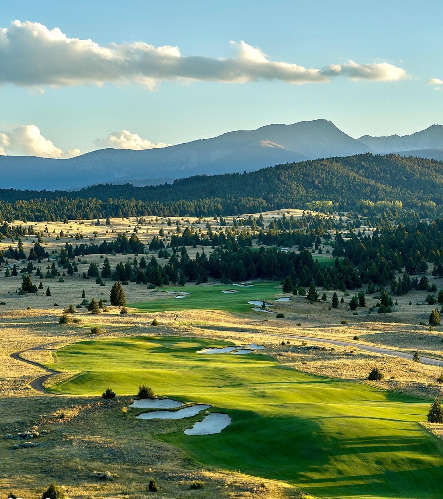 An aerial view of a golf course with mountains in the background