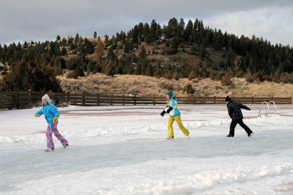 Three people are ice skating on a frozen lake