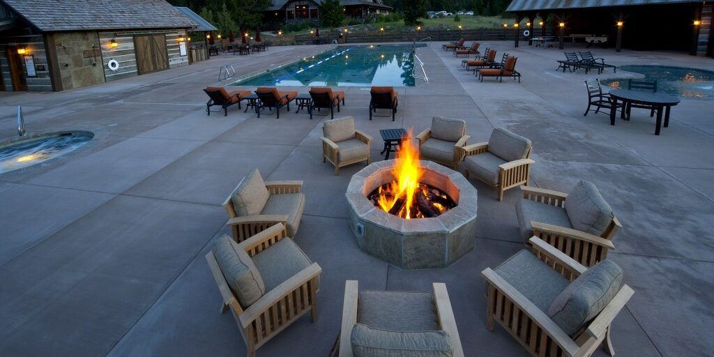 A fire pit surrounded by chairs and a swimming pool