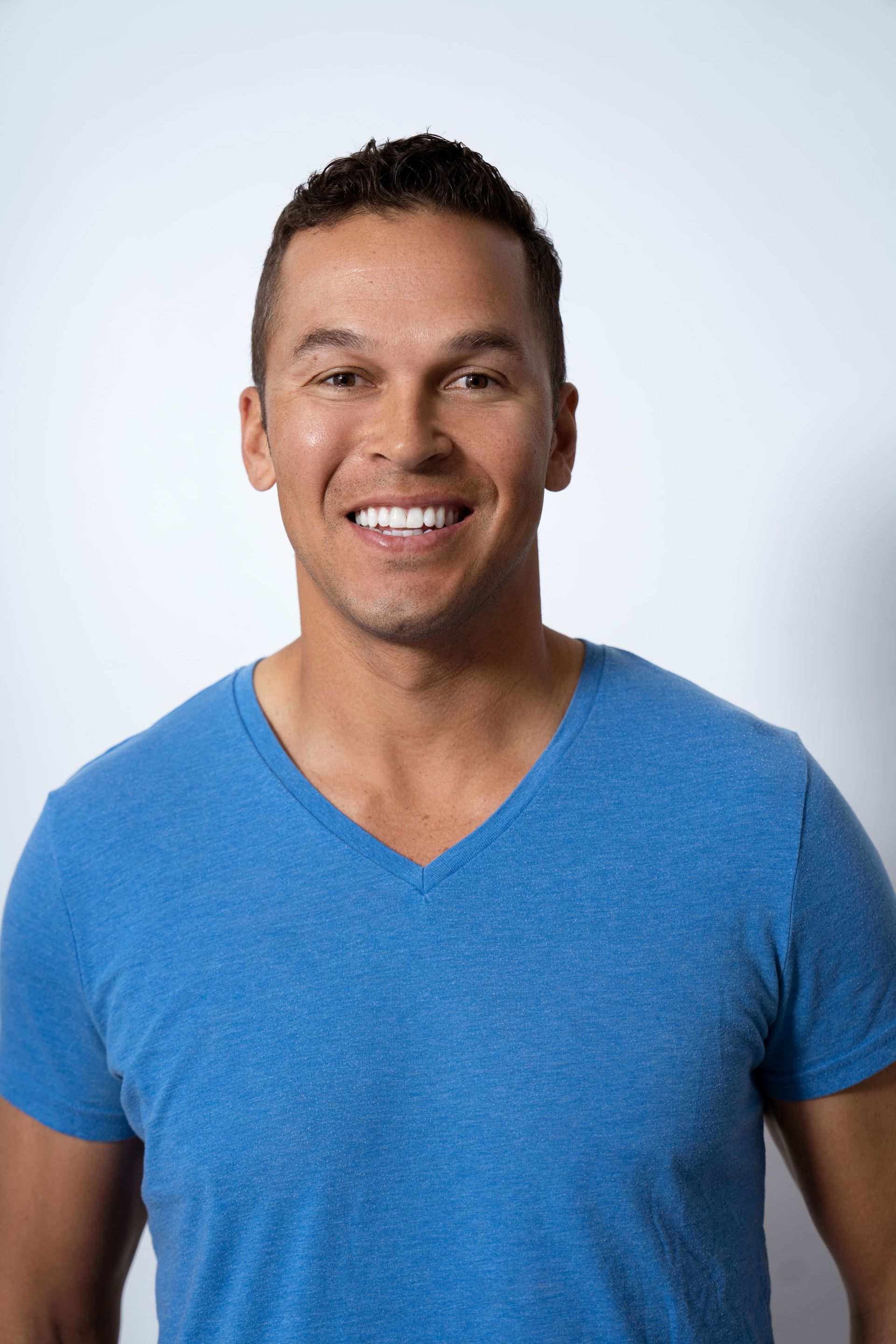 A man in a black polo shirt is smiling for the camera.