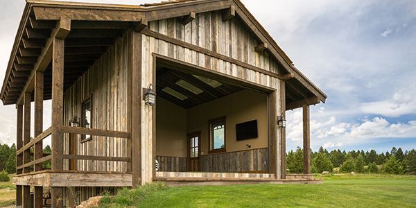 A small wooden house with a porch and a television inside of it.